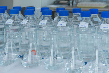 Laboratory equipment. Laboratory storage bottles with blue polypropylene cap on white table.