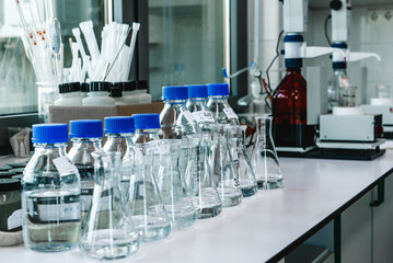 Laboratory equipment. Laboratory storage bottles with blue polypropylene cap on white table.