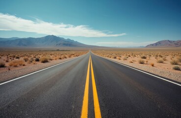 Naklejka premium Summer view of asphalt road in desert with yellow center line. Mountain range, land horizon, blue sky. Empty highway offers freedom, adventure. Travel to New Mexico USA.