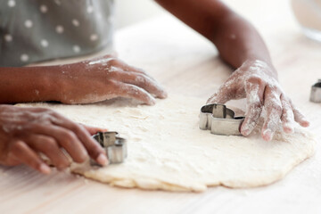 Cropped of african american family mother and daughter making diverse figures with cookie cutters, unrecognizable black mom and kid baking together at home, using biscuit figurines, baking concept