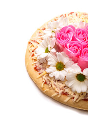Pink roses in heart love shape and white chamomile flowers on top of a pizza and on white background. Abstract conceptual art. Selective focus.