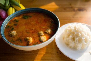 Tom yam restaurant soup in a bowl. Hot spicy dish with rice on the table
