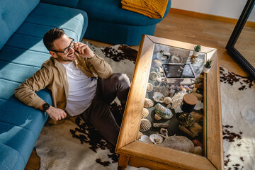 Adult man sit on the living room floor and talk via video call