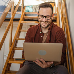 Adult caucasian man sit and work on laptop read report on the stairs