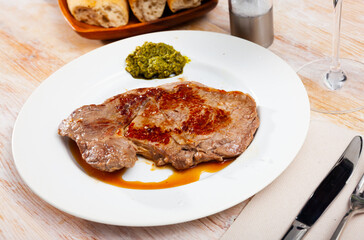 Appetizing beef entrecote served with salsa verde sauce