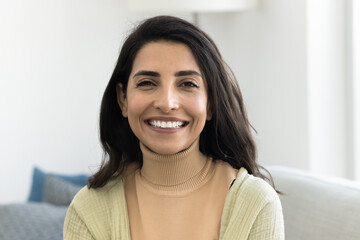 Head shot profile picture of beautiful Brazilian woman revealing white teeth while smiling at...