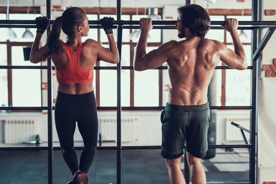 man and woman in gym doing pull ups - Powered by Adobe
