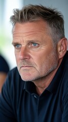 Obraz premium A man with a bald head and a beard is looking at the camera. He has a serious expression on his face