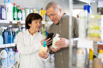 Obraz premium Couple elderly man and woman buyers scanning qr code for liquid hand soap in household chemicals store