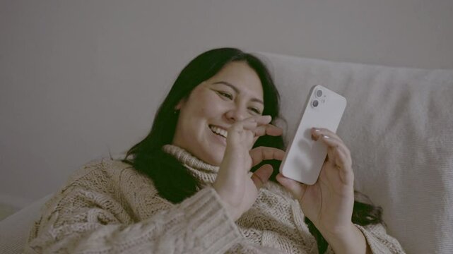 Woman, smile at meme on social media and smartphone, scroll online with communication at home. Female person using phone, connectivity and search web with internet, technology and reading chat