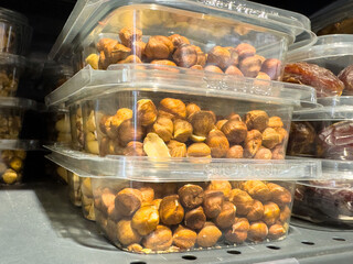 Plastic containers filled with fresh hazelnuts stacked on market shelf