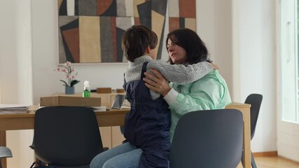 Mother hugging child warmly while seated at table, strong emotional connection and bonding moment captured in affectionate embrace, showcasing family love and closeness