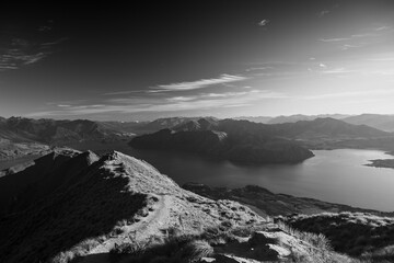 Black and white shot of silhouettes of people on the top an a mountain with an incredible view