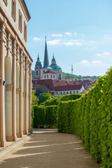 Obraz premium Beautiful garden path with historical buildings in Prag under clear blue sky