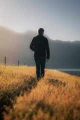 A man takes a walk in the countryside at sunset.