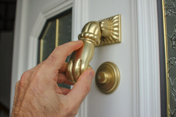 an adult hand in a door knocker