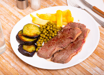 Roasted juicy beef with potatoes, eggplant and peas cooked in a restaurant