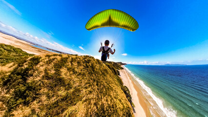 Extreme paragliding pilot soaring in the New Zealand beach. Adventure concept.