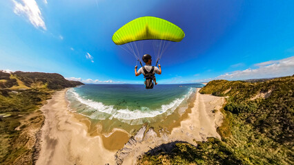 Extreme paragliding pilot soaring in the New Zealand beach. Adventure concept.