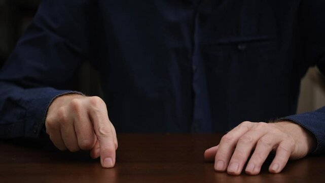 close-up of an unrecognizable upset businessman nervously tapping his index finger on the table. meeting plan, valuable instructions, debriefing. a hand gesture. front view.