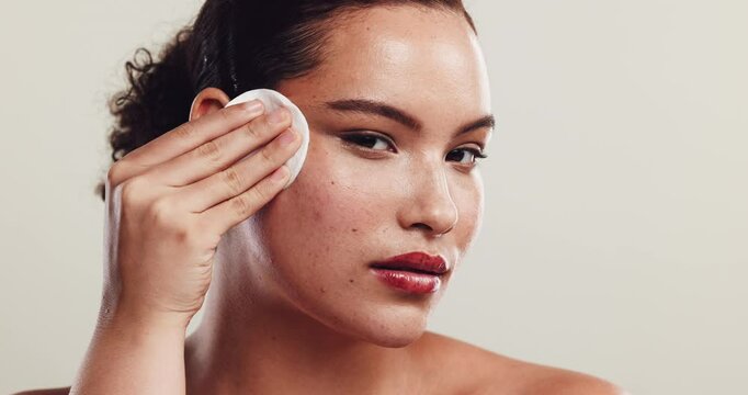 Woman, beauty and cotton pad with makeup for cosmetic removal, skincare or facial on a white studio background. Portrait, female person and applying with pigmentation for cosmetology or face cleanse
