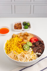 Soto Mie Bogor. Traditional Sundanese Beef Noodle Soup with Spring Roll, Cabbage, and Tomato. Street Food from Bogor, West Java, Indonesia. Perfect for recipe, article, catalogue.