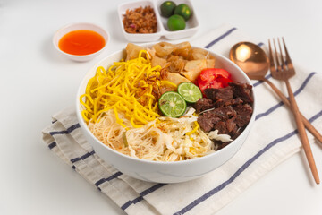 Soto Mie Bogor. Traditional Sundanese Beef Noodle Soup with Spring Roll, Cabbage, and Tomato. Street Food from Bogor, West Java, Indonesia. Perfect for recipe, article, catalogue.