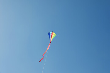 One colorful kite flying in blue sky