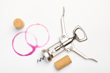 Wing corkscrew, corks and red wine stains on white background, top view