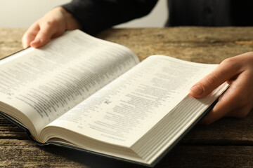 Naklejka premium Woman with Holy Bible in English language at wooden table, closeup