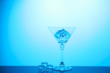 Cocktail glass with ice cubes on table, color tone effect