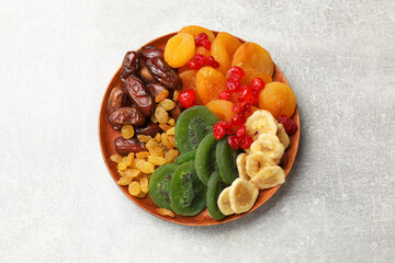 Mix of different dried fruits in bowl on light grey table, top view