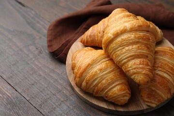 Tasty fresh croissants on wooden table, closeup. Space for text