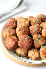 Tasty cooked meatballs with green onion in bowl on white table, closeup