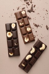 Tasty chocolate bars and crumbs on beige background, flat lay