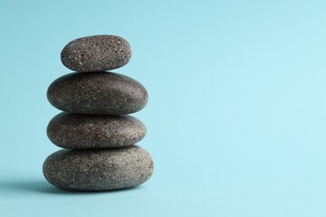 Stack of rocks on light blue background, space for text. Harmony and life balance