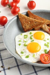 Tasty fried eggs with toasts served on table, closeup