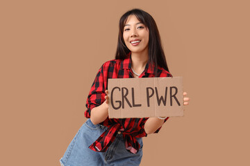Young happy Asian woman holding paper with text GIRL POWER on beige background. Women's history...