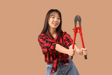 Beautiful young happy Asian woman with bolt cutter on beige background. Women's history month