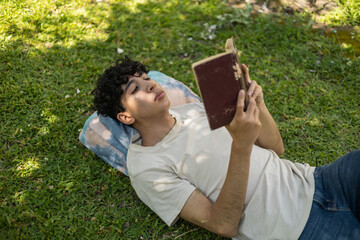 A person relaxing in the park, enjoying their favorite novel. Perfect for themes of leisure,...