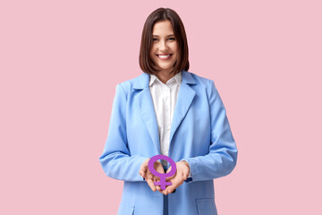 Beautiful young woman holding female symbol on pink background. Women's history month