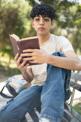 Fototapeta premium Enjoying a peaceful moment in the park, reading a book under the sun, perfect for themes like relaxation, outdoor activities, and leisure time.