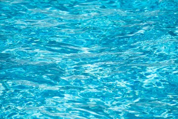 Water background. Blue water, ripples and highlights. Texture of water surface and tiled bottom.