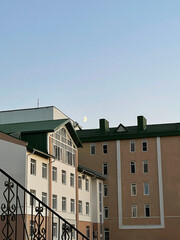 An aesthetically beautiful landscape with modern houses at sunset, the early moon is visible in the sky. evening photo