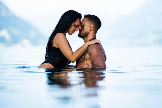 Attractive couple in passionate embrace in water. Beautiful young woman and her sexy boyfriend touching each other on the beach. Fashion models. Summer vacation on the beach. Erotic couple.