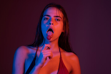 Beautiful woman with a lollipop. Sensual lips and playful licking. Desire and passion with a lollipop. Close-up of female mouth with lollypop. Sensual woman enjoying a sweet. Glossy lips and sugar.