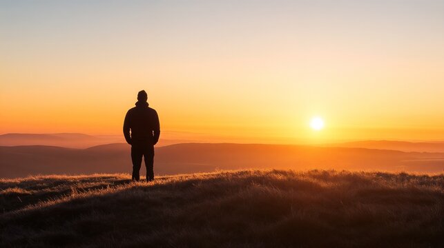 Silhouette of person watching sunrise over mountain landscape. Great for inspiration, adventure, and personal achievement themes.