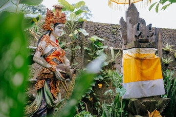A beautiful Balinese statue of Dewi Danu, the goddess of water, standing gracefully in a lush...