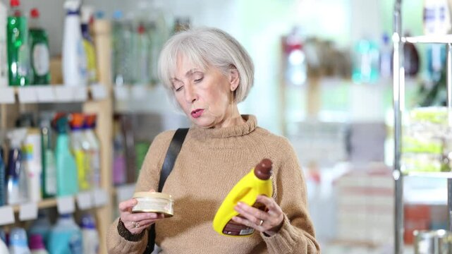 Elderly housewife buys a cleaning product for washing parquet and laminate floors in a supermarket. High quality 4k footage