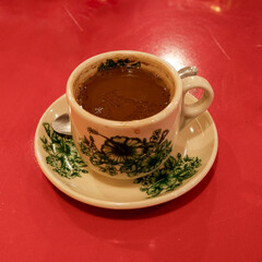 a cup of chinese coffee with red metal table